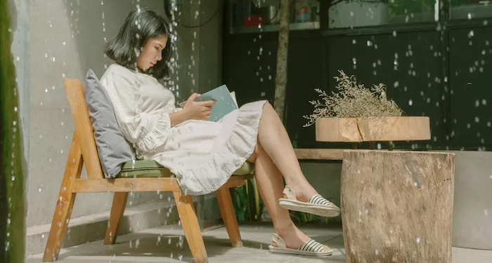 a photo of a woman sitting in a chair and reading with water falling in lines in the foreground